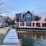 View from the dock to the back of newly constructed home on the Chesapeake Bay for modern coastal designed by 2e Architects